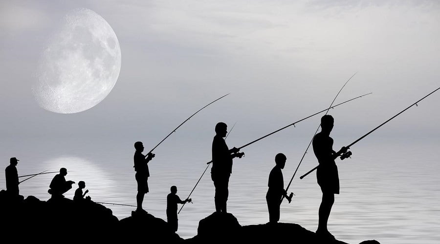 Silhouettes of people fishing under the moon