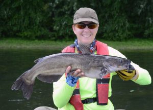 Happy angler with catfish caught near a dam